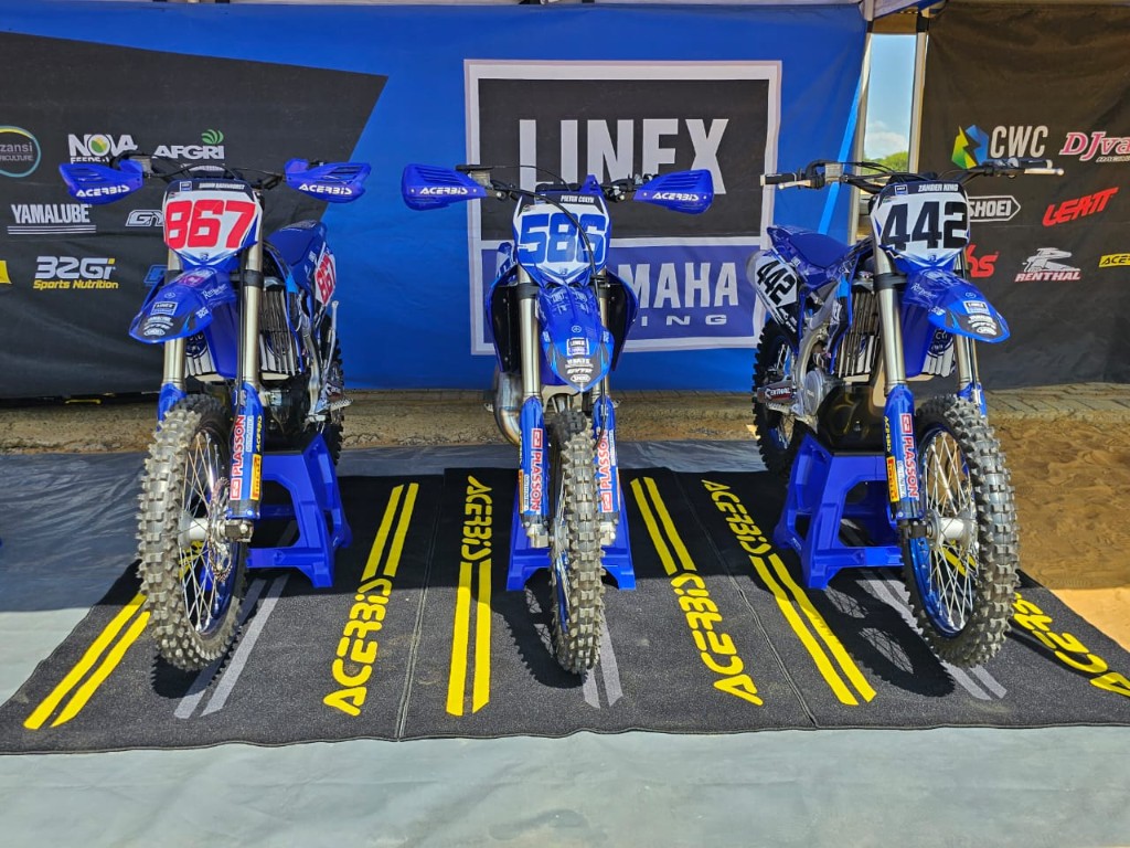 Three Yamaha motocross bikes on Acerbis mats with LINEX YAMAHA RACING backdrop by Plan Photo Repro